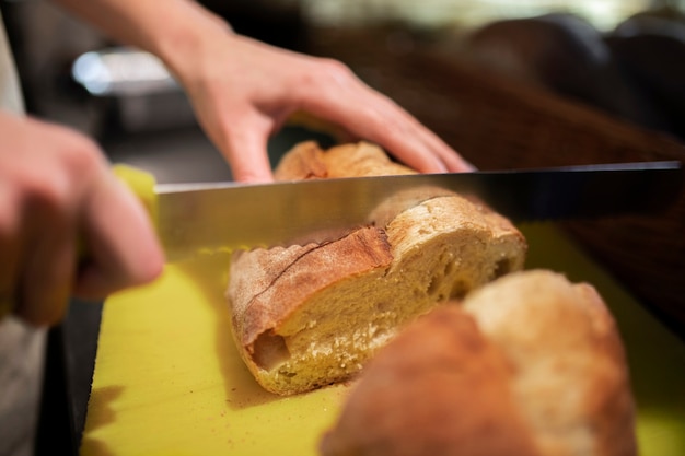 Close up hand cutting bread