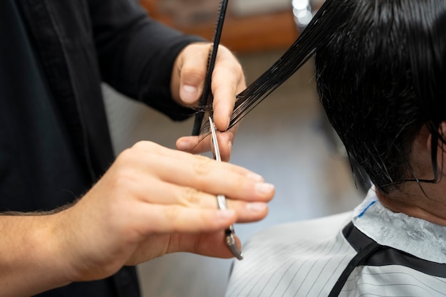 Close up hand cutting hair with scissors