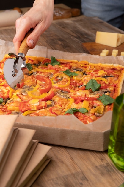 Free photo close up hand cutting pizza with tool