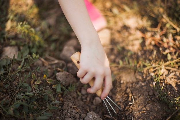 Close-up of hand digging the soil with gardening fork