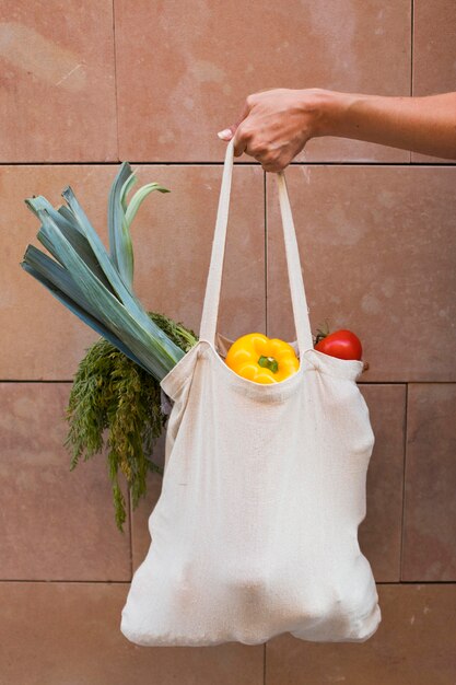 Close up hand holding bag with vegetables