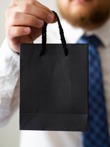 Free photo close-up hand holding a black bag mock-up