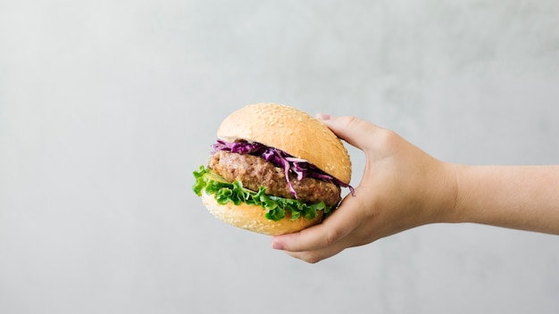 Free photo close-up hand holding burger