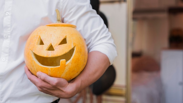 Free Photo close-up hand holding carved pumpkin