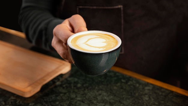 Free photo close-up hand holding coffee with milk cream