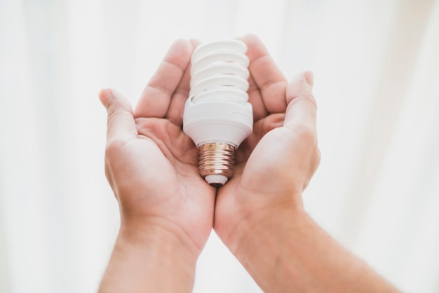 Free Photo close-up of hand holding compact fluorescent light bulb