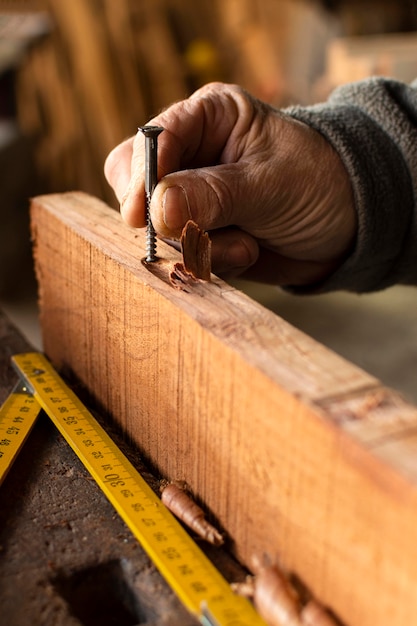 Free Photo close-up hand holding a nail in wood