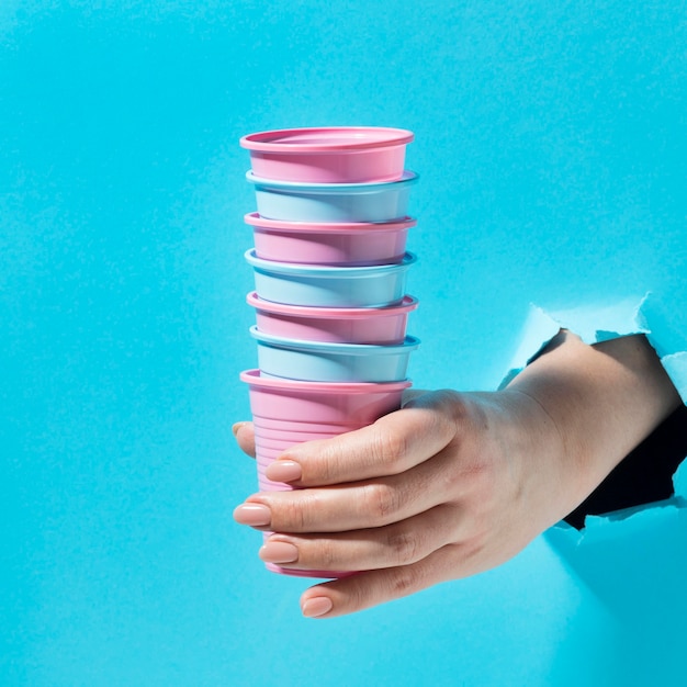 Close-up hand holding pile of plastic cups