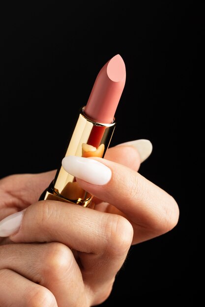 Close up hand holding pink lipstick