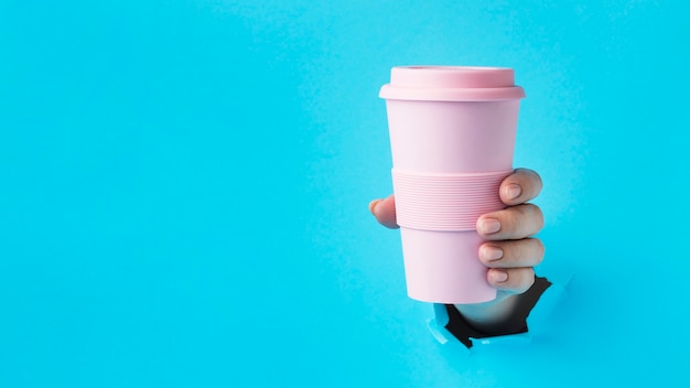 Close-up hand holding reusable cup with copy space