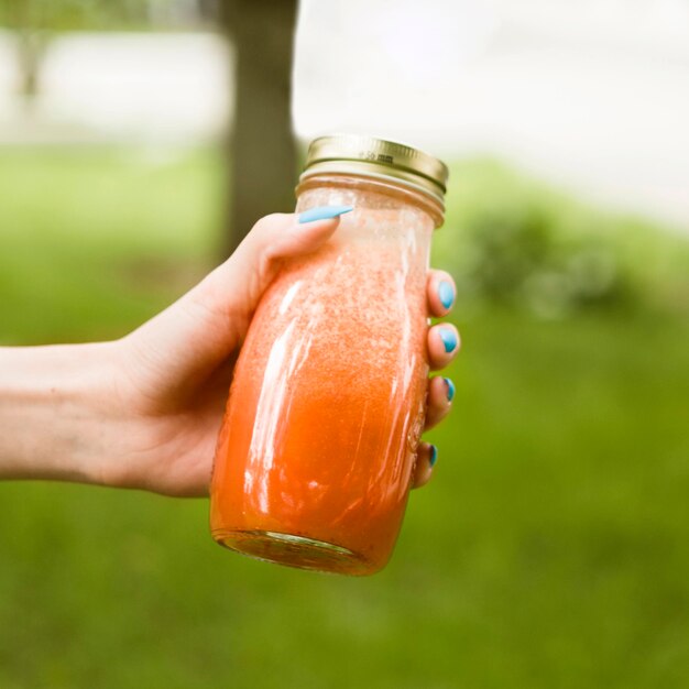 Close-up hand holding smoothie bottle