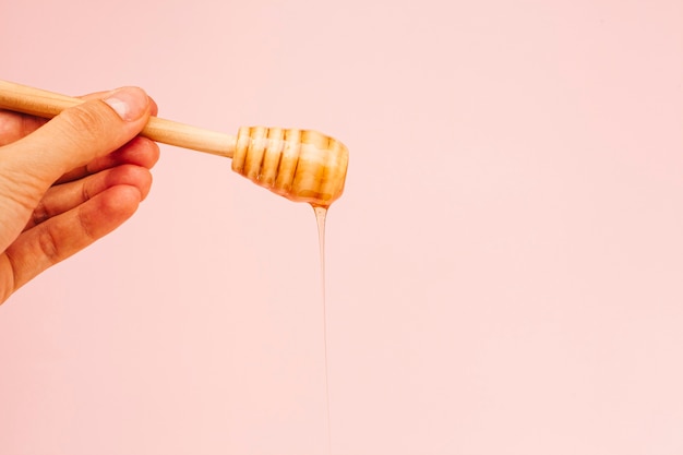 Close-up hand holding tasty honey stick