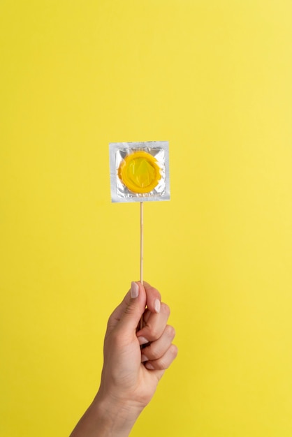 Close up hand holding yellow condom