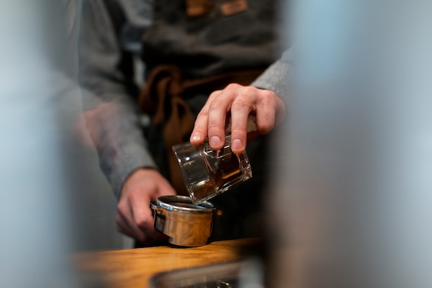 Free Photo close-up of hand pouring coffee in pot