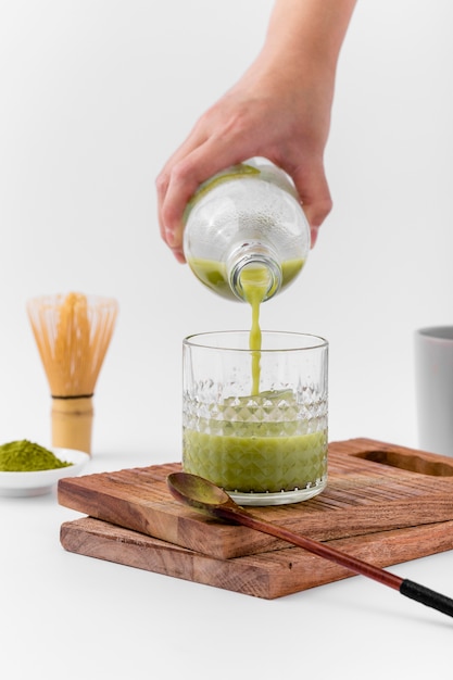 Free Photo close-up hand pouring matcha tea into glass