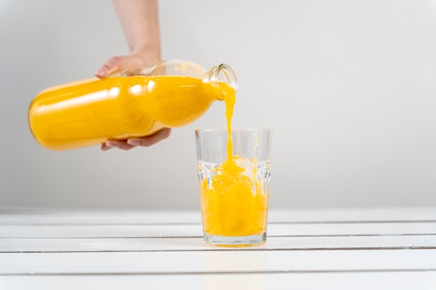 Free photo close-up hand pouring orange juice in glass