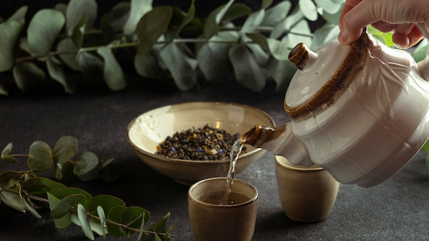 Free Photo close-up hand pouring tea in cup