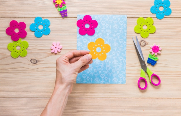 Close-up of hand preparing greeting card on wooden table