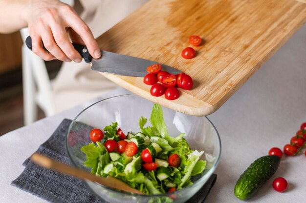 Close up hand putting tomatoes in salad