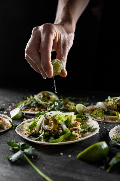 Close-up hand squeezing lime on taco