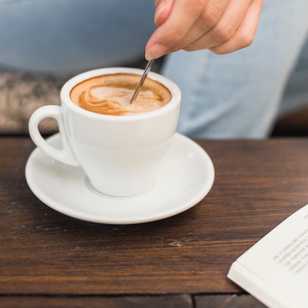 Free photo close-up of hand stirring spoon in cup of coffee