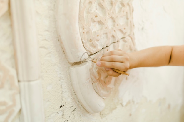 Close-up of hand using tool for carving on wall