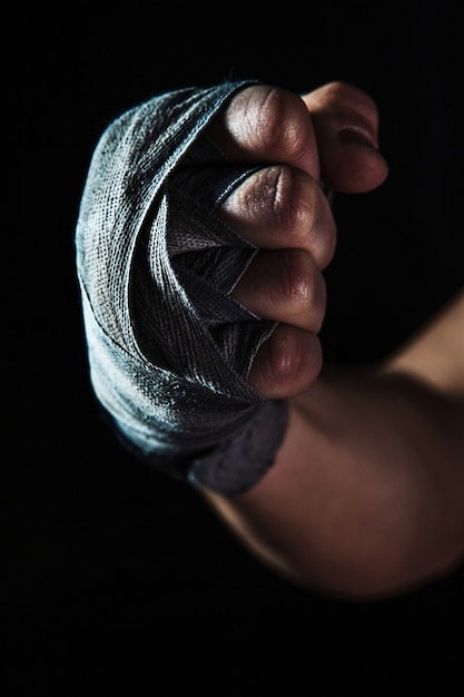 Free Photo close-up hand with bandage of muscular man training kickboxing  on black