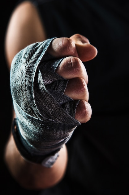 Close-up hand with bandage of muscular man training kickboxing on black