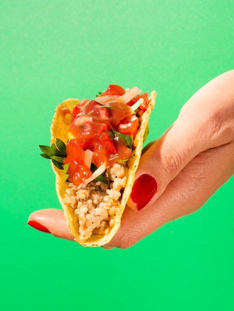 Close-up hand with taco and green background