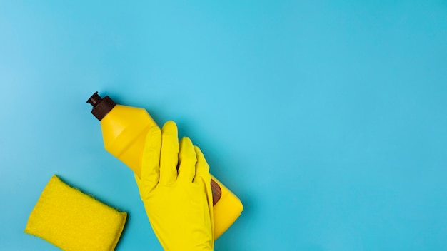 Free photo close-up hand with yellow glove on blue background