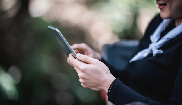 Close up hand of Young pretty woman sitting in chair and use tablet with happy while camping in nature park copy space