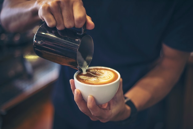 Free photo close-up of hands barista make latte coffee art paint