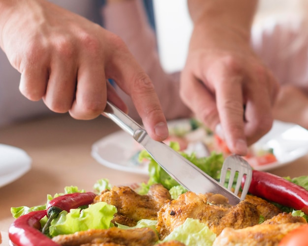 Close-up hands cutting meat