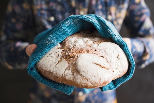 Close-up of hands holding baked bread wrapped in blue napkin