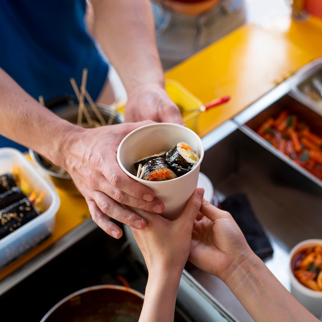 Free photo close up hands holding cup with sushi