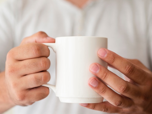 Free photo close-up hands holding a mug mock-up