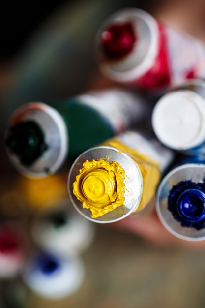 Close up of hands holding oil paints, palette wall