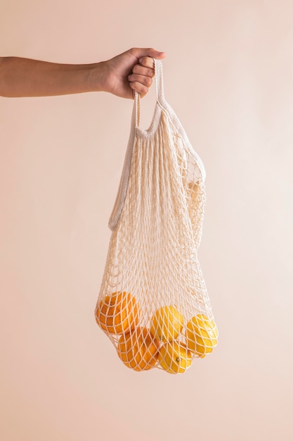 Close-up hands holding oranges bag