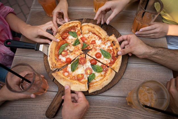 Free photo close up hands holding pizza slices