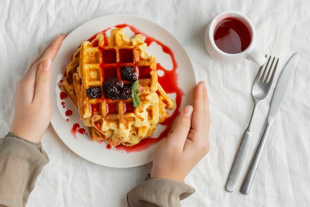 Free photo close-up hands holding plate with waffles