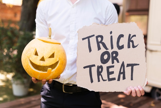 Free Photo close-up hands holding pumpkin and sign