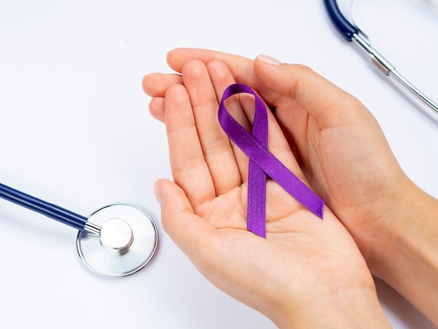 Free Photo close-up hands holding purple ribbon with stethoscope