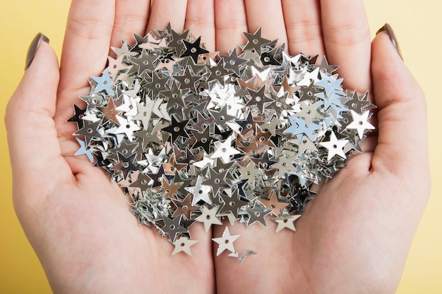 Close-up hands holding silver star sequins