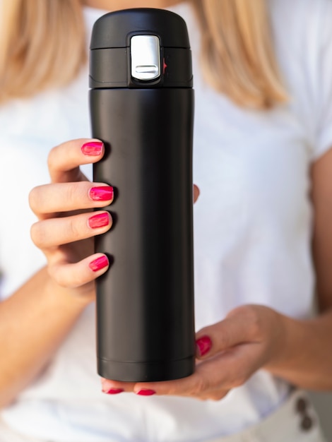 Close-up hands holding a thermos mock-up