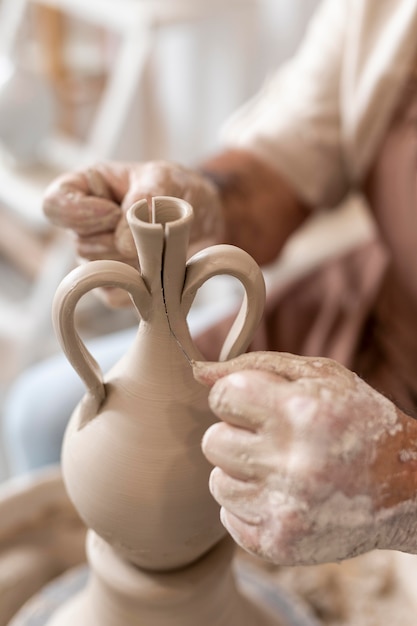 Free photo close up hands making clay pot