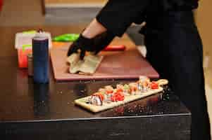 Free photo close up hands of professional chef wear in black gloves making sushi and rolls in a restaurant kitchen of japanese traditional food