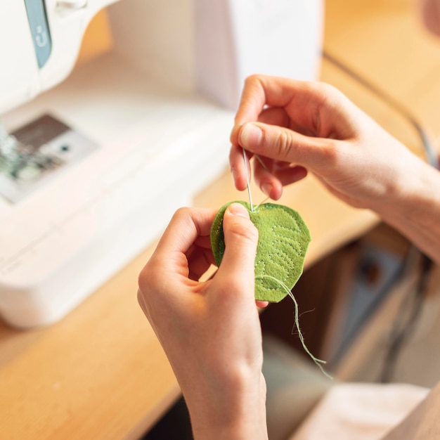 Free photo close-up hands sewing leaf with needle