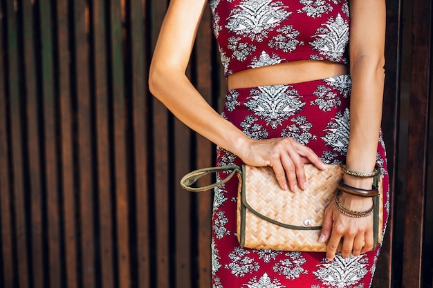 Close up hands of stylish woman holding straw handbag