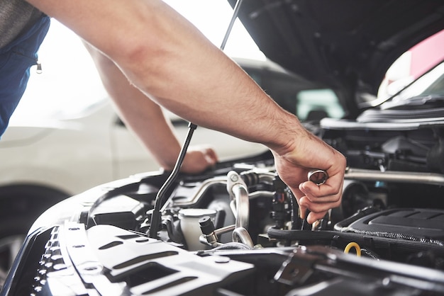 Close up hands of unrecognizable mechanic doing car service and maintenance.