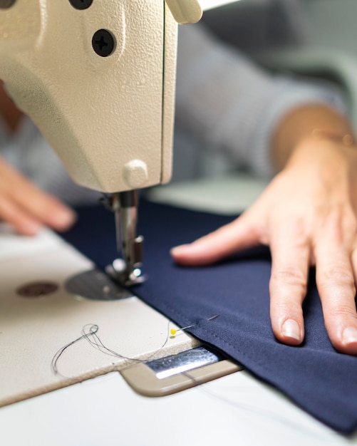 Free photo close-up hands using sewing machine